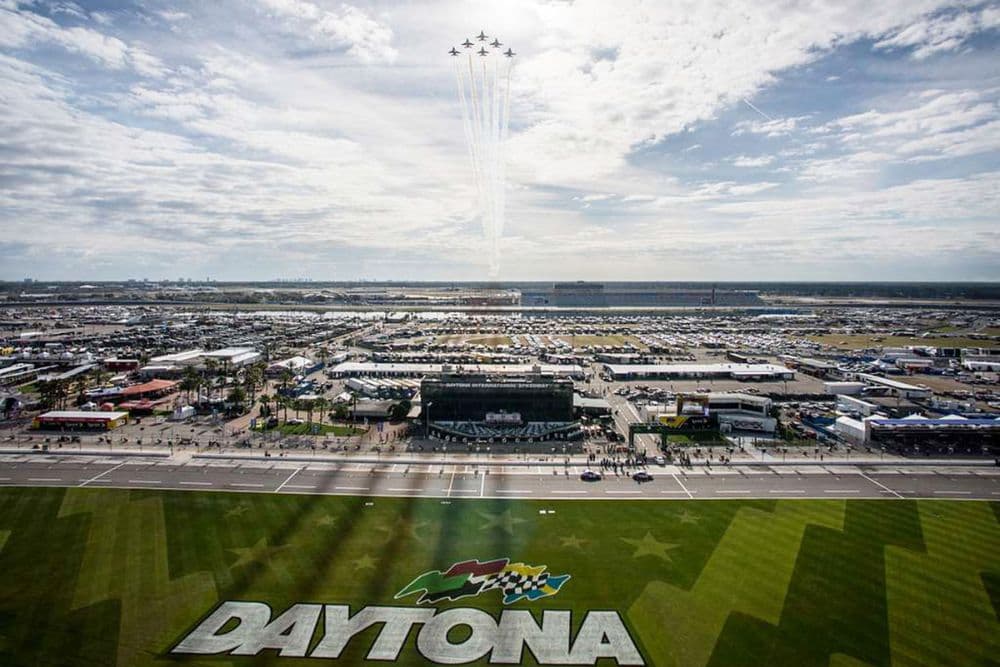 Aerial view of the Daytona International Speedway with a jet flyover and the word "DAYTONA" painted on the grass.