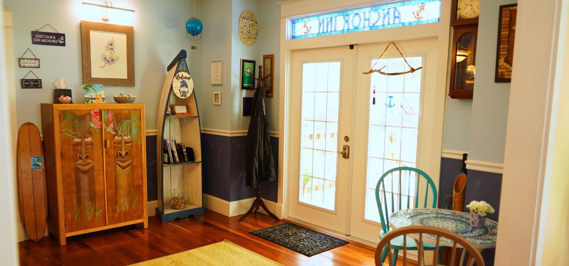 A cozy entryway featuring wooden decor, a blue-painted chair, and a glass-panel door with nautical-themed details.