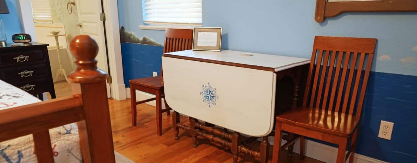 Bedroom with bed, dropleaf table wth two chairs, doorway into attached bathroom