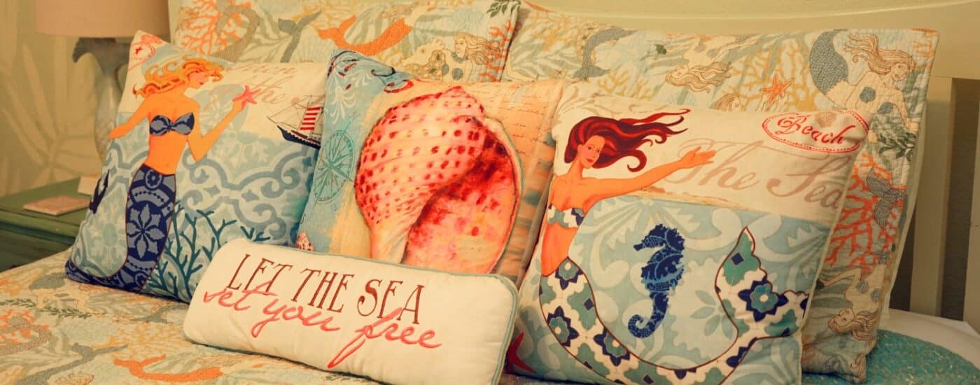 Bed with plush and colorful pillows with mermaids and seashell designs