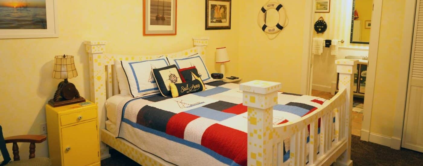 Bedroom with queen bed in patchwork quilt, side tables with lamps and doorway into attached bathroom