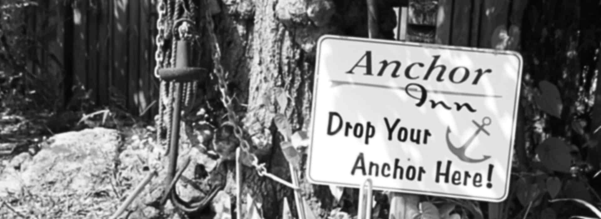 A black and white photograph showing a sign posted by a tree for an Inn