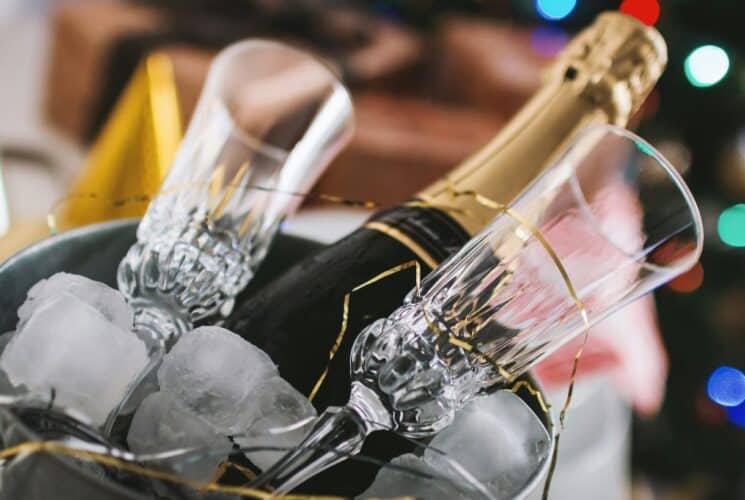 A bottle of champagne and two glass flutes in a silver bucket with ice