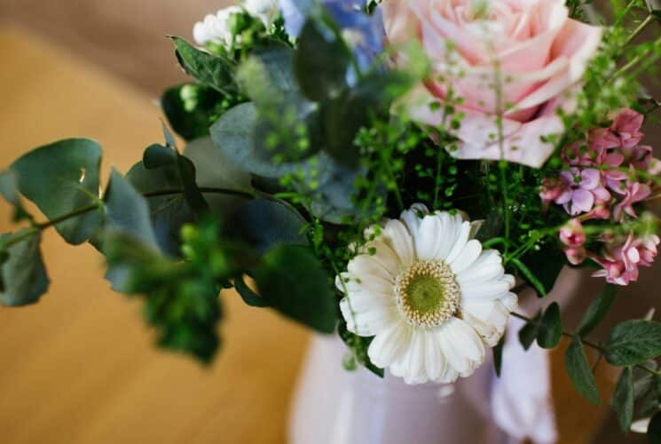 A bouquet of flowers, daisies, roses and hydrangeas, with greens in a vase